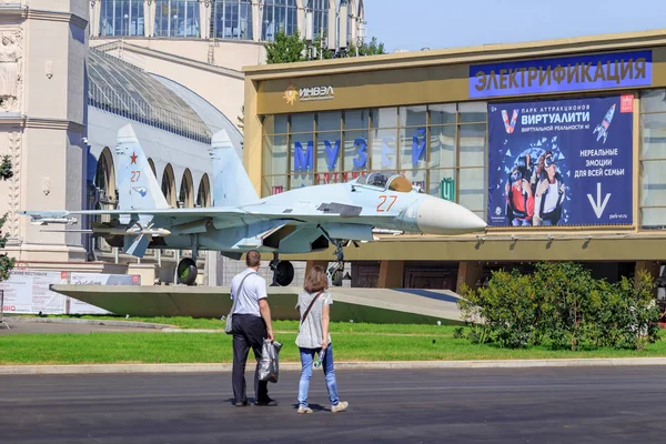 Moscow, Russia - August 01, 2018: Tourist walking near russian fighter SU-27 on Exhibition of Achievements of National Economy (VDNH) in Moscow on a sunny summer morning