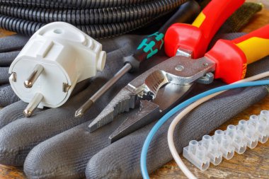 Kombinasyon pense bir tornavida, elektrik prizinden ve atölyede ahşap masa çalışma eldiven terminalde tel kablo