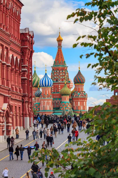 Moscow, Russia - September 30, 2018: Tourists walk on Red Square near wall of State Historical Museum on a background of St. Basil Cathedral in sunny day — Stock Photo, Image