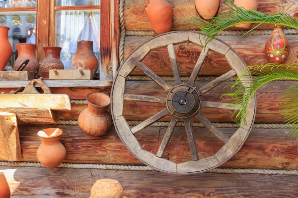 Fachwerkwand eines Dorfhauses mit Tonkrügen und Wagenrad bei sonnigem Tag — Stockfoto