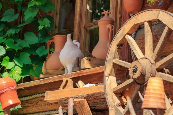 Blick auf die Fachwerkwand eines Dorfhauses mit Tonkrügen und Wagenrad — Stockfoto