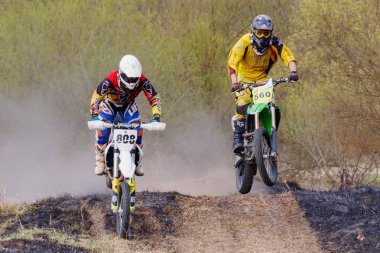 Moskova, Rusya - 13 Nisan 2019: Kros motosikletli iki yarışçı toprak piste atladı. Motokros spor takımının eğitimi