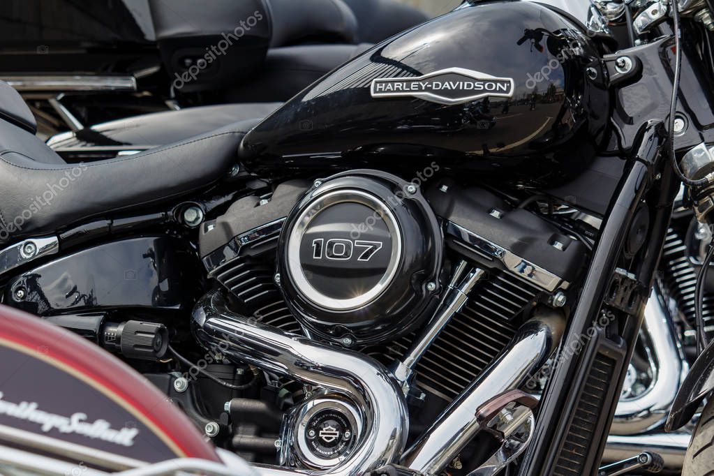 Moscow, Russia - May 04, 2019: Glossy black fuel tank with Harley Davidson motorcycles emblem with matte black engine and chromed exhaust system pipes closeup. Moto festival MosMotoFest 2019