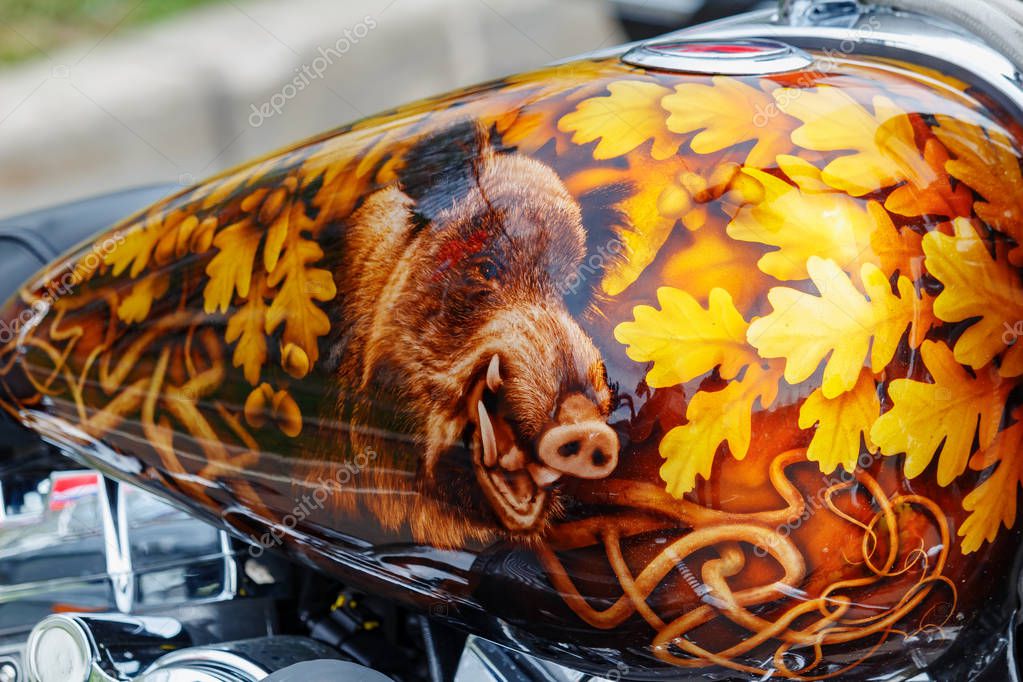 Moscow, Russia - May 04, 2019: Harley Davidson motorcycle with airbrushing of wild boar in oak leaves on fuel tank closeup. Moto festival MosMotoFest 2019