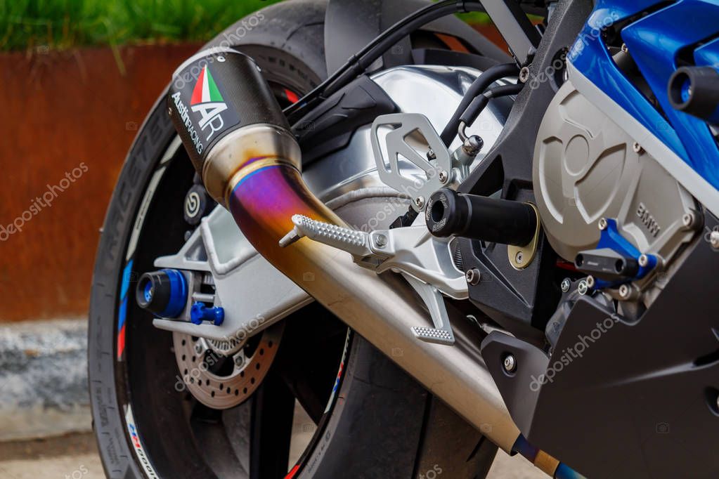 Moscow, Russia - May 04, 2019: Rear wheel with disc brake system and matte chromed exhaust system pipe of BMW sports motorcycle closeup. Moto festival MosMotoFest 2019