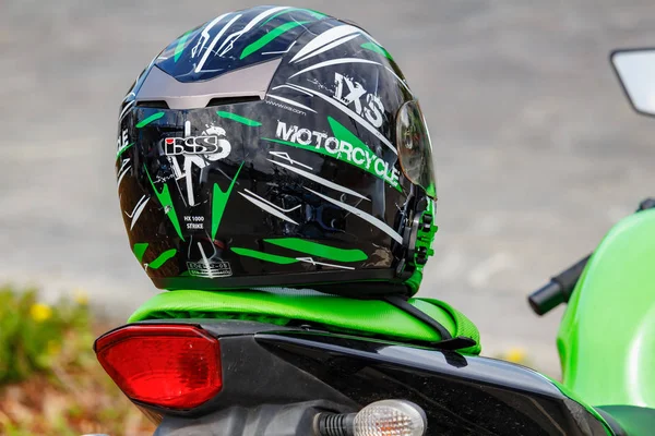 Москва, Росія-04 травня 2019: чорний спорт мотоцикл шолом Ixs з зеленими смугами лежить на зеленому шкіряний сидіння мотоцикла крупним планом. Мото фестиваль Mosmotofest 2019 — стокове фото