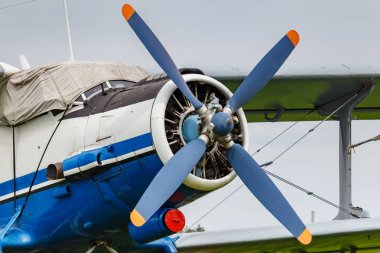 Beyaz ve mavi Sovyet çift kanatlı uçak Antonov An-2 havaalanı otoparkında bulutlu gökyüzüne yakın çekim yapıyor.