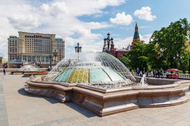 Moskova, Rusya - 02 Haziran 2019: Moskova'daki Manezhnaya Meydanı'nda, güneşli yaz sabahında mavi gökyüzüne karşı Four Seasons Hotel ve State Historical Museum'un arka planında kubbe çeşmesi