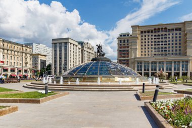 Moskova, Rusya - 02 Haziran 2019: Güneşli yaz sabahında Moskova'daki Manezhnaya Meydanı'nda Four Seasons Hotel ve Rusya Federasyonu Devlet Dumuası'nın arka planında dünyanın Çeşme Saati