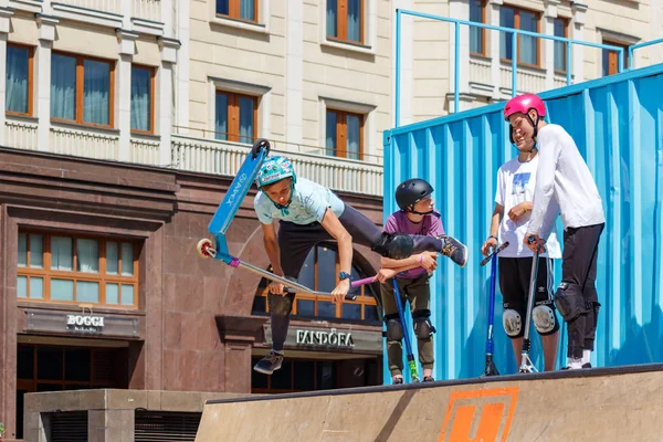 Moscow, Russia - June 02, 2019: Young flatland riders on sports scooters performs tricks at ramp on Manezhnaya Square in Moscow at sunny summer day. Festival Fish week in Moscow 2019 — Stock Photo, Image