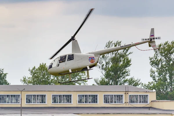 Balashikha, Moscow Region, Rusland-25 mei 2019: Helicopter Robinson R44 Raven Ra-06359 vliegt tegen de bouw en groene bomen over vliegveld Chyornoe bij de luchtvaart Festival hemel theorie en praktijk — Stockfoto