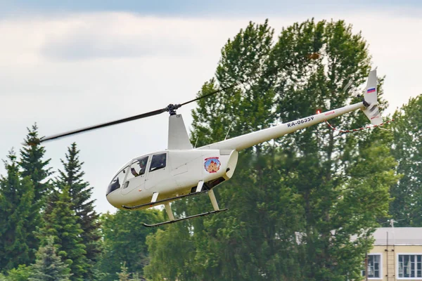 Balashikha, Moscow Region, Rusland-25 mei 2019: Helicopter Robinson R44 Raven Ra-06359 vliegt tegen groene bomen over vliegveld Chyornoe bij de luchtvaart Festival hemel theorie en praktijk 2019 — Stockfoto