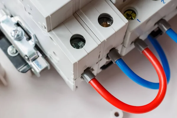 Connected ports of automatic circuit breakers by red and blue wires closeup