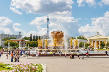 Moskova, Rusya-Temmuz 22, 2019: Moskova 'da VDNH Park halkların dostluk Çeşmesi güneşli yaz gününde beyaz bulutlar ile mavi gökyüzüne karşı Ostankinskaya TV Kulesi bir arka plan üzerinde