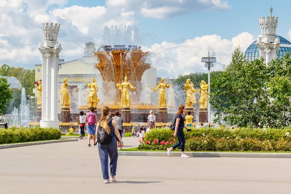 Moscú, Rusia - 22 de julio de 2019: Turistas caminando contra la fuente de la Amistad de los Pueblos en el parque VDNH en Moscú en el soleado día de verano. El parque VDNH es un popular punto de referencia turístico — Foto de Stock