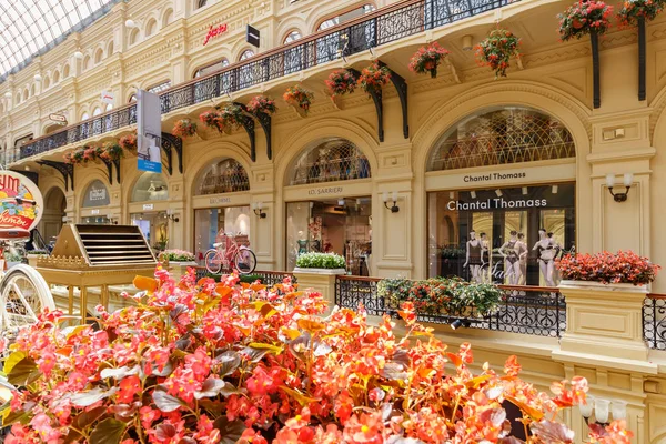 Moscú, Rusia - 28 de julio de 2019: Flores contra escaparates de boutiques en GUM State Department Store en el soleado día de verano. Interiores de GUM en la Plaza Roja de Moscú — Foto de Stock