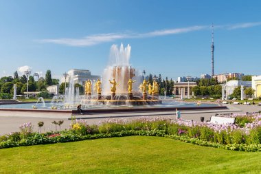 Moskova, Rusya - 22 Temmuz 2019: Güneşli yaz gününde mavi bir gökyüzü arka plan üzerinde Moskova'da Vdnh parkta çiçeklerle yeşil çimler karşı Halkların Dostluk çeşme