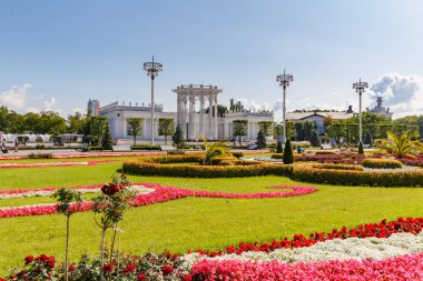 Moskova, Rusya - 22 Temmuz 2019: Güneşli yaz sabahında Moskova'daki Vdnh parkında pavyonlara karşı çiçeklerle süslenmiş yeşil çimler. Vdnh dış