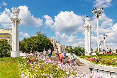 Moskova, Rusya - 22 Temmuz 2019: Güneşli yaz sabahında Moskova'daki Vdnh parkında çimlere karşı sokakta yürüyen turistler. Vdnh popüler turistik yerdir