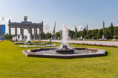 Moskova, Rusya - 22 Temmuz 2019: Güneşli yaz sabahında ana girişin kavisine karşı Moskova'daki Vdnh parkında ana sokakta çeşmeler çalışıyor