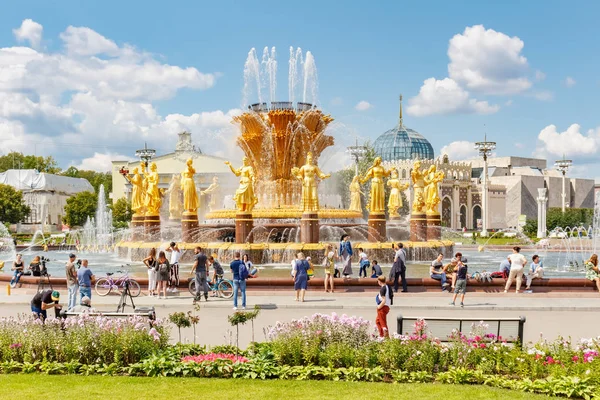 Moscú, Rusia - 22 de julio de 2019: Los turistas descansan y toman una foto cerca de la fuente de la Amistad de los Pueblos en el parque VDNH en Moscú en el soleado día de verano. El parque VDNH es un popular punto de referencia turístico — Foto de Stock