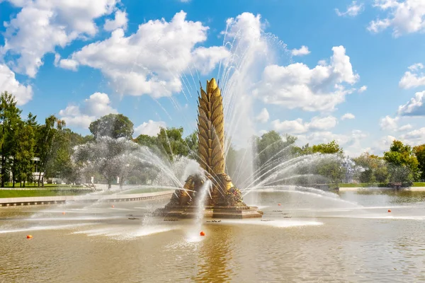 Moscú, Rusia - 22 de julio de 2019: Fuente Golden Spike en el estanque Kamensky en el parque VDNH en Moscú contra el cielo azul con nubes blancas. Parque VDNH en el soleado día de verano — Foto de Stock