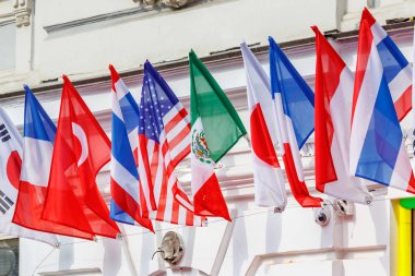 Güneşli bir günde bina duvarına üst üste ası farklı ülkelerin bayrakları ası