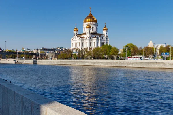 Catedral de Cristo Salvador en Moscú contra el terraplén del río Moskva en la soleada mañana de primavera sobre un fondo azul del cielo — Foto de Stock