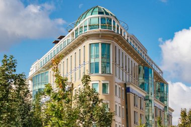 Moskova, Rusya - 21 Eylül 2019: Moskova şehir merkezinde güneşli sonbahar sabahında yeşil ağaçlara ve mavi gökyüzüne karşı modern konut binasının cephesi