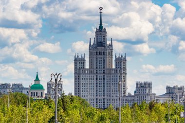 Moskova, Rusya - 02 Haziran 2019: Moskova'daki Kotelnicheskaya dolgusundaki Stalin gökdeleni yeşil ağaçlara ve beyaz bulutlarla mavi gökyüzüne karşı. Yaz günü Zaryadye Park'tan görünüm