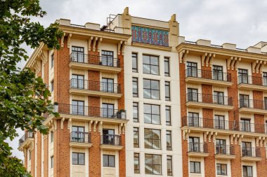 Moskova, Rusya - 13 Ağustos 2019: Yaz aylarında yeşil ağaç ve bulutlu gökyüzüne karşı çağdaş konut binasının cephesi. Moskova mimarisi