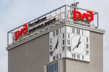 Moskova, Rusya - 21 Eylül 2019: Çatıda Rzd Rus demiryolu tabelaları, duvarlarda bulutlu sokak saatleri olan gri beton kule