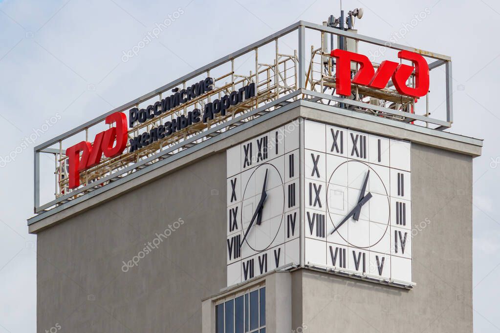 Moscow, Russia - September 21, 2019: Grey concrete tower with RZD Russian railways signboards on the roof and street clocks on the walls against sky with clouds