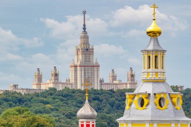 Moskova, Rusya - 13 Ağustos 2019: Moskova 'daki Sparrow Hills' teki Lomonosov Moskova Devlet Üniversitesi binası, yaz sabahı ortodoks kiliselerinin renkli kubbelerine karşı. Moskova 'nın ünlü Panoraması