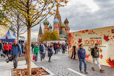 Moskova, Rusya - 05 Ekim 2019: Kızıl Meydan 'da Aziz Basil Katedrali' ne karşı düzenlenen geleneksel Altın Sonbahar festivalinin reklam panosu yakınında yürüyen ziyaretçiler