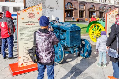 Moskova, Rusya - 08 Ekim 2019: Moskova 'daki Devrim Meydanı' nda tarım makineleri sergisi ziyaretçileri, yenilenmiş Amerikan tekerlek traktörü Fordson F 'nin fotoğrafını çekti