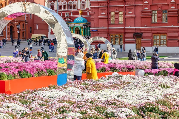 Moskova, Rusya - 08 Ekim 2019: Güneşli sonbahar gününde Moskova 'daki Manezhnaya Meydanı' nda yürüyen insanlar. Geleneksel Altın Sonbahar festivalinde çiçeklerin dekoratif kurulumları — Stok fotoğraf