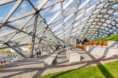 Moskova, Rusya - 08 Ekim 2019: Zaryadye Park 'taki Büyük Amfitiyatronun Mimarisi. Sonbahar günü güneş ışığında, bir yamaçta cam çatı ve ahşap banklar.