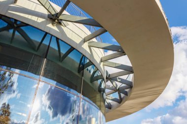 Moskova, Rusya - 08 Ekim 2019: Güneşli bir günde kavisli camlarla çağdaş bina cephesi. Beyaz bulutlu mavi gökyüzü modern binanın camlarına yansıyor.