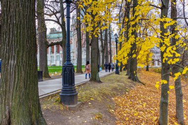 Moskova, Rusya - 16 Ekim 2019: Moskova 'daki Tsaritsyno Parkı' nda sonbahar günü tarihi binalara karşı sokaklarda yürüyen turistler. Ağaçların arasından bak