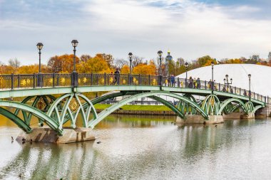 Moskova, Rusya - 16 Ekim 2019: İnsanlar bulutlu bir sonbahar gününde Tsaritsyno Parkı 'ndaki Orta Göl üzerindeki yaya köprüsünde yürüyor. Tsaritsyno Park Moskova 'da popüler bir turistik yerdir.