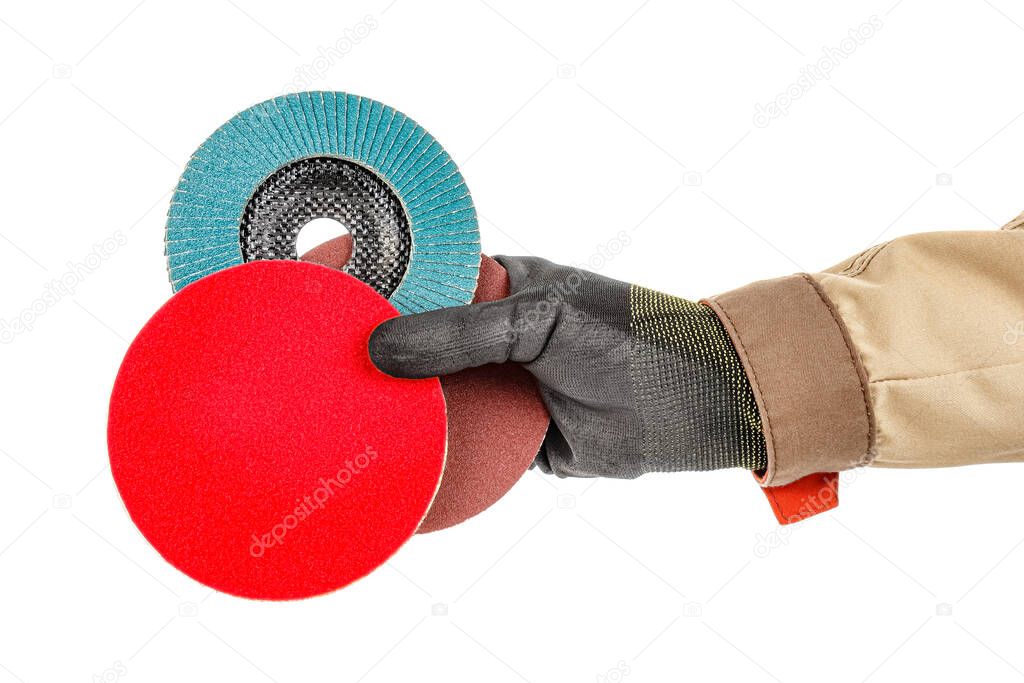 Bright red polishing disc with blue abrasive flap disc and sanding paper disc in worker hand in black protective glove and brown uniform isolated on white background