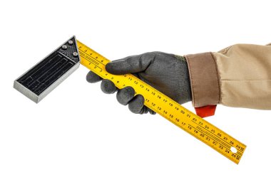 Marangoz eli siyah koruyucu eldiven ve kahverengi üniforma içinde sarı metali tutan sağ açılı cetvel beyaz arka planda izole edilmiş.