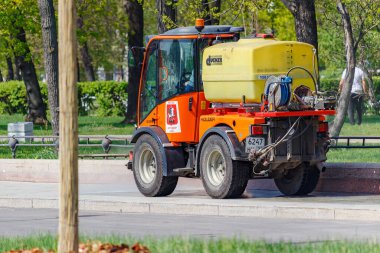 Moskova, Rusya - 01 Mayıs 2019: Güneşli bir bahar sabahı yol kaldırımında plastik su tankı taşıyan küçük turuncu fıskiye kamyonu