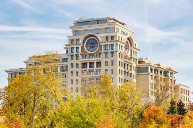 Moskova, Rusya - 3 Ekim 2019: Moskova mimarisi. Sonbahar ağaçlarına karşı güneşli bir sonbahar gününde renkli yapraklı modern konut binası