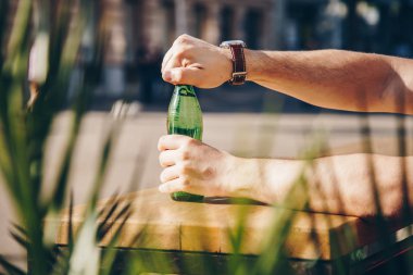 Genç adam açılış su şişesi üzerinde bir güneşli gün outoors