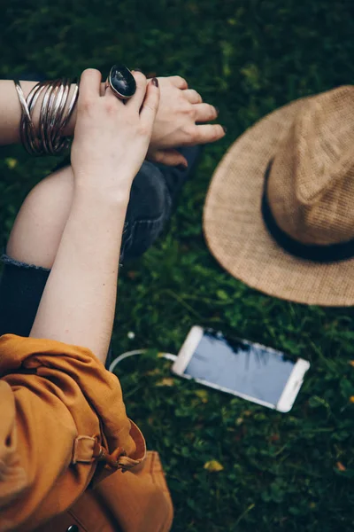 一个女人戴着戒指 在她的智能手机上听音乐的特写 街道风格细节的一个波西米亚别致的音乐节女性配件 理想的夏季装备 女孩坐在草地上 — 图库照片