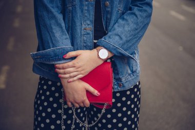 kırmızı çanta tutarak ve bir gül altın bilek saati denim ceket şık kadın. sokak stil moda