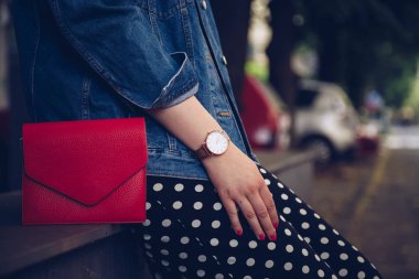 kırmızı çanta tutarak ve bir gül altın bilek saati denim ceket şık kadın. sokak stil moda