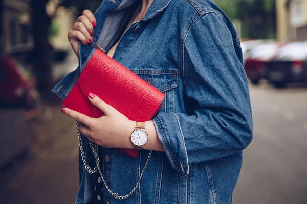 赤い財布を押しながらバラの金の腕時計を身に着けているデニム ジャケットでスタイリッシュな女性 ストリート スタイル ファッション — ストック写真